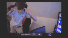 a computer screen shows a man wearing a white polo shirt and headphones