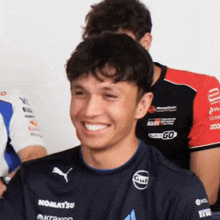 a man wearing a shirt that says komatsu and gulf smiles