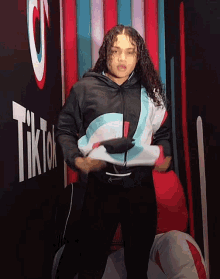 a woman stands in front of a wall that says tik tok