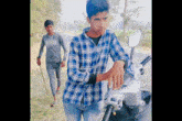 a man in a plaid shirt is standing next to a motorcycle