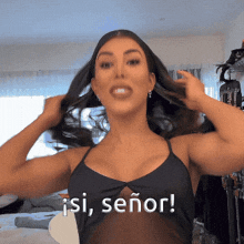 a woman in a black tank top holds her hair and says " isi señor "