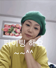 a woman wearing a green hat and a yellow sweater with korean writing on it