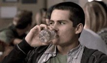 a young man drinking from a plastic bottle