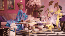 two women are sitting at a table in a living room with a netflix logo on the bottom