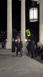 a man wearing a green mask with the letter e on it stands in front of a group of people