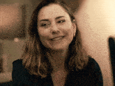 a woman wearing a black shirt and earrings smiles at the camera
