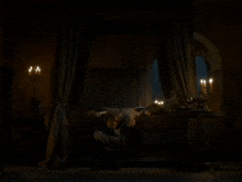 two people laying on a canopy bed with candles