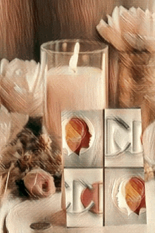 a candle in a glass surrounded by flowers and a few boxes with faces on them