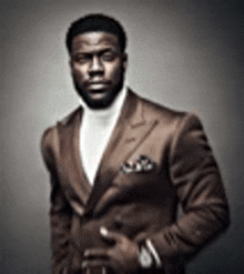 a man in a suit and turtleneck is standing in front of a gray wall .