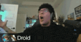 a man wearing headphones and glasses is screaming in front of a sign that says droid