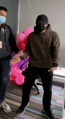 a man wearing a mask is dancing in front of a bunch of balloons