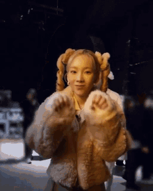 a woman wearing a fur coat with pigtails on her hair .