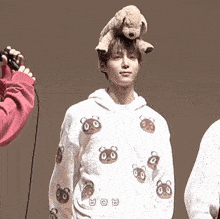 a man with a teddy bear on his head wearing a white hoodie