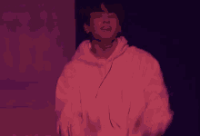a young man in a white hoodie is dancing on a stage in a dark room .