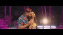 a man with red hair is kissing a woman in a yellow bikini .