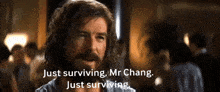 a man with long hair and a beard says just surviving