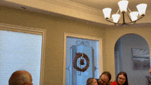 a group of people are sitting at a table with a wreath on the door .