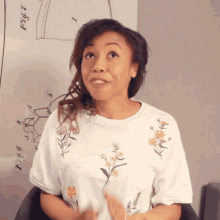 a woman in a white shirt with yellow flowers on it