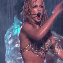 a woman in a bikini is singing into a microphone on a stage in the rain .