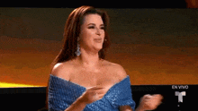 a woman in a blue dress is sitting in front of a screen .