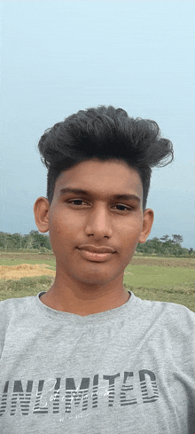 a young man wearing an unlimited t-shirt poses for a picture