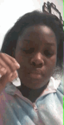 a girl in a pink and blue hoodie is making a funny face