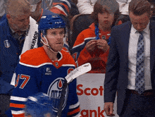 a hockey player with the number 17 on his jersey is standing next to a man in a suit