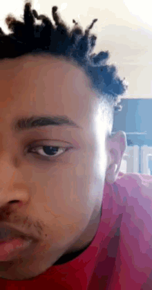 a close up of a young man 's face with a red shirt on