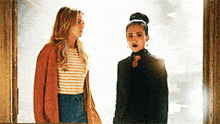 two women are standing next to each other in a doorway and talking .