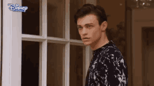 a young man is standing in front of a door with a disney channel logo on it