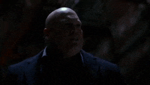 a man in a black suit is holding a knife in a dark room .