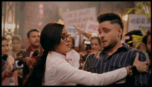 a man and a woman are talking in front of a crowd with a sign in the background that says ' a ' on it