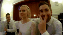 a man is giving a peace sign while a woman looks on
