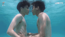 two young men are kissing underwater in a swimming pool .