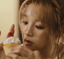 a close up of a woman eating an ice cream cone with whipped cream and strawberries on it