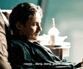 a man in a green robe is laying on a couch and saying " i know sorry sorry guys "