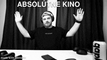 a black and white photo of a man with his arms outstretched and the words absolutne kino above him