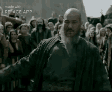 a man with a beard and a bald head is standing in front of a crowd of people .