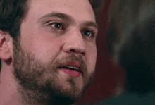 a close up of a man 's face with a beard looking at the camera .
