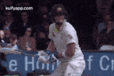 a cricket player wearing a helmet is swinging a bat at a ball .