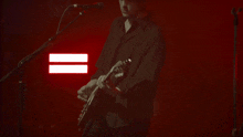 a man in a black shirt is playing a guitar in front of a microphone