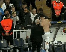 a shirtless man stands in front of a bench that says fenerbahce gifs