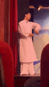 a man in a white dress is standing on a stage