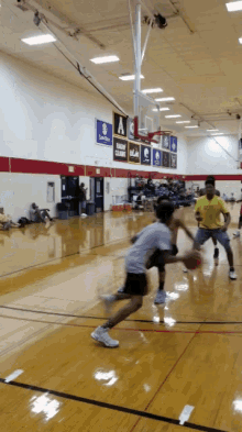 a man in a yellow shirt is dribbling a basketball in a gym