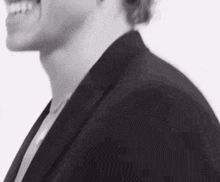 a black and white photo of a man in a suit and tie smiling .