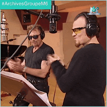 two men wearing headphones and sunglasses are standing in front of a microphone with the hashtag #archivesgroupem6 above them