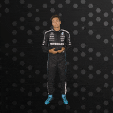 a man in a petronas jumpsuit is standing in front of a black background