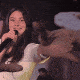 a woman singing into a microphone with a hand reaching out