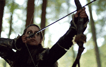 a woman is holding a bow and arrow in her hand