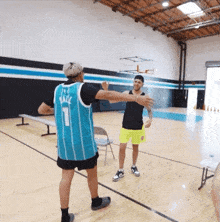 a man wearing a number 1 jersey talks to another man on a basketball court